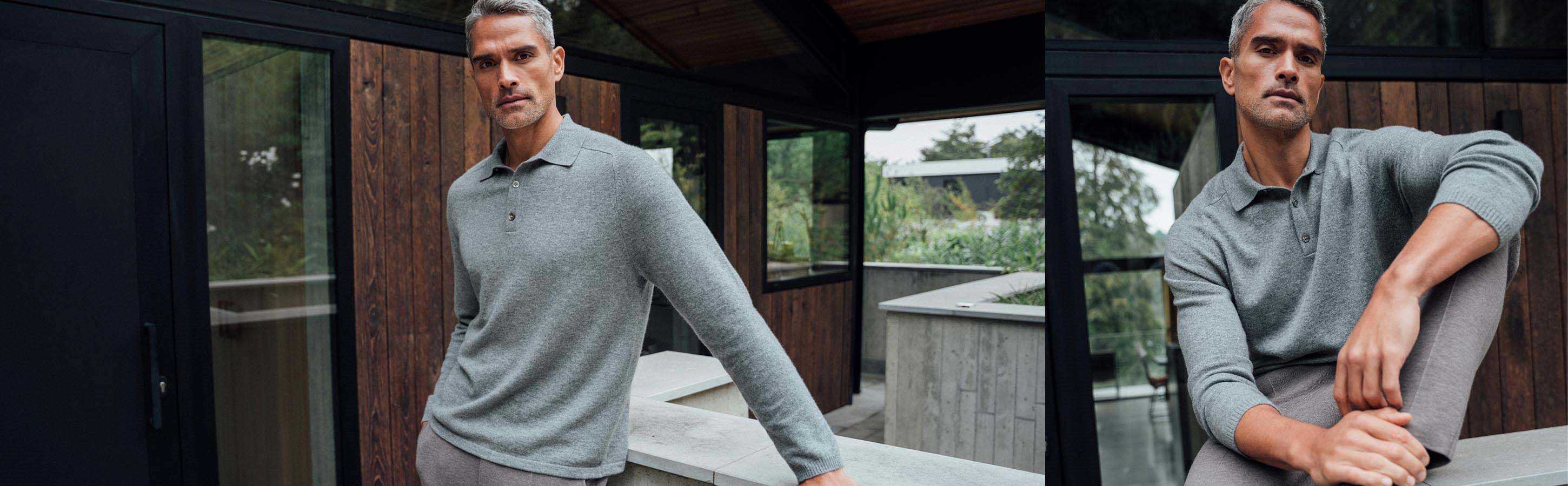 Mann trägt graues Cashmere Poloshirt und graue Hose vor moderner Holzfassade.