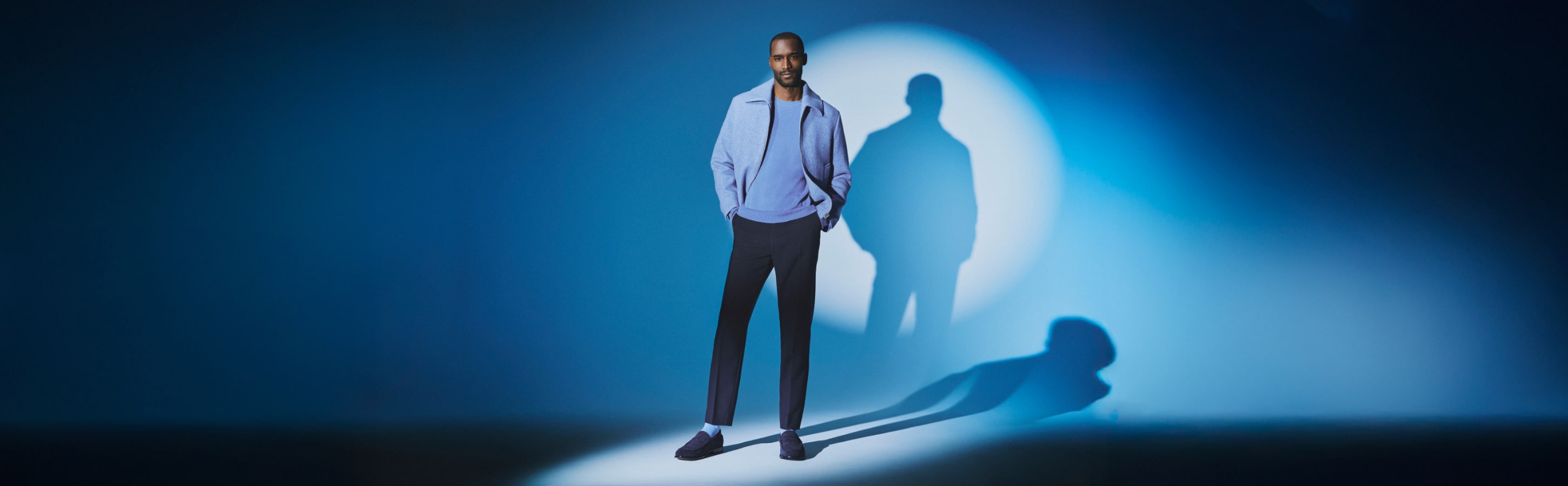 Mann trägt blaue Socken der Serie Clima Wool von FALKE Mann trägt blaue Socken der Serie Clima Wool von FALKE und steht in blauer Kleidung vor einer blauen Wand