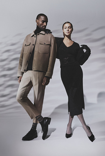 Mann in beigefarbener Jacke und heller Hose mit FALKE Socken neben Frau in schwarzem Kleid und Strumpfhose FALKE 2025 Kollektion