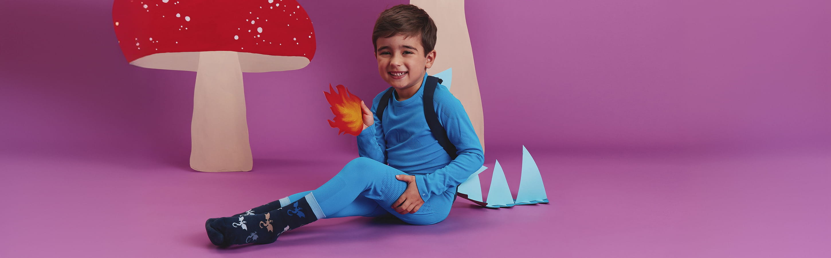 FALKE Flying Dragon Kinder Socken Kind trägt FALKE Flying Dragon Socken mit bunten Drachenmotiven zu einem blauen Drachenkostüm