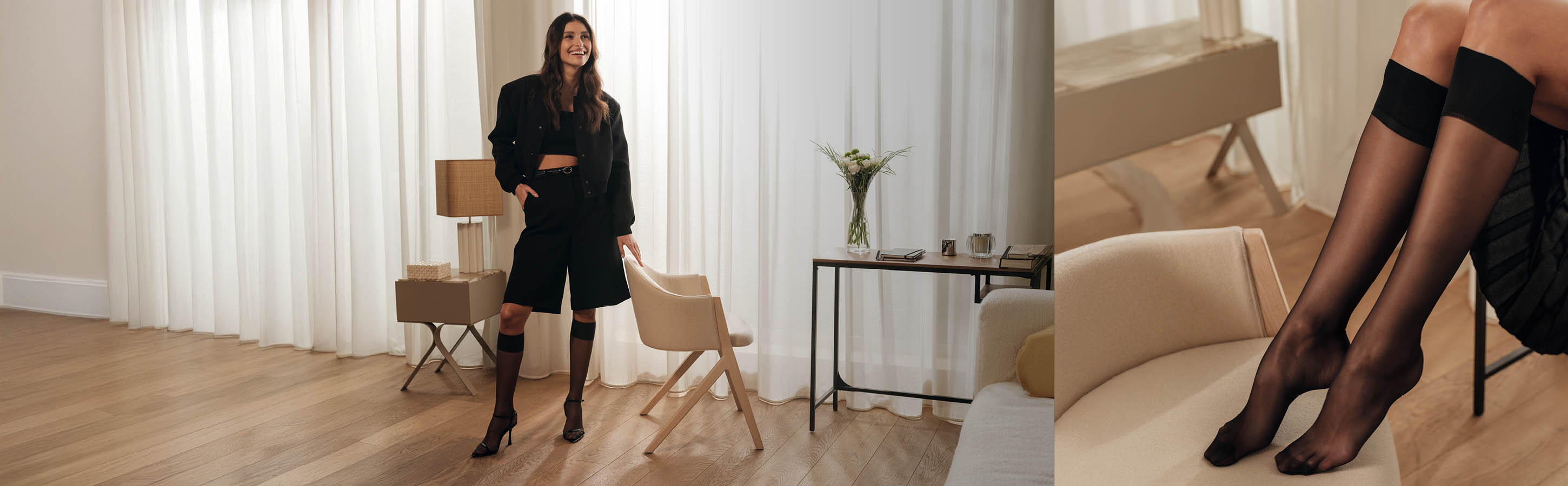Frau trägt schwarze transparente FALKE Seidenglatt Kniestrümpfe und ein modernes schwarzes Outfit in einem hellen Wohnzimmer mit Holzfußboden