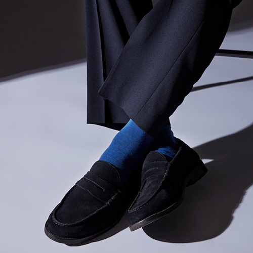 Nahaufnahme von strahlend blauen Herrensocken in schwarzen Schuhen